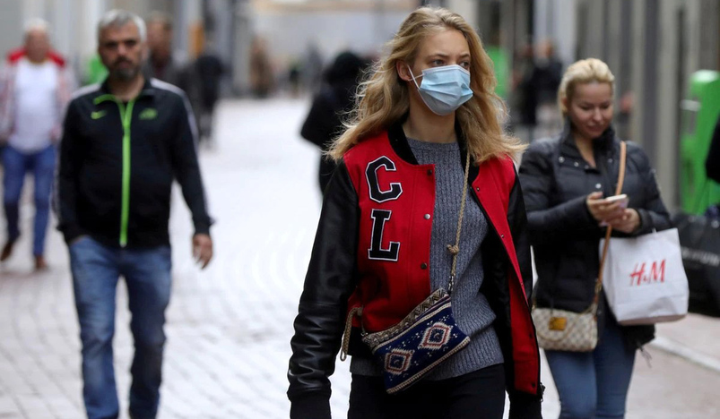 People with and without protective masks walk on the street in Amsterdam